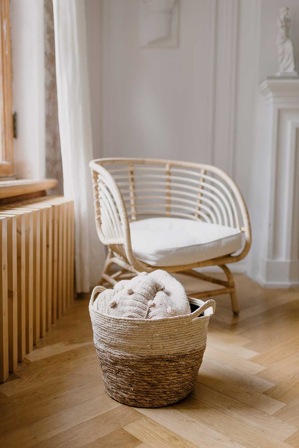 cream colored chair and basked with blankets